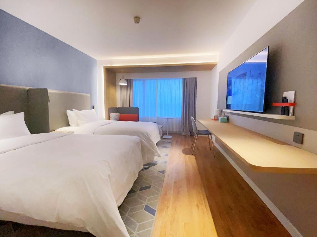 呼和浩特呼和浩特东站智选假日酒店的酒店客房设有两张床和一台平面电视。