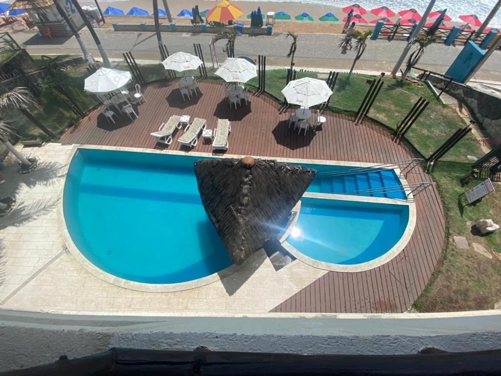 纳塔尔Flat Beira Mar- Ap 306 #ELEGANCE的享有带椅子和遮阳伞的游泳池的上方景致