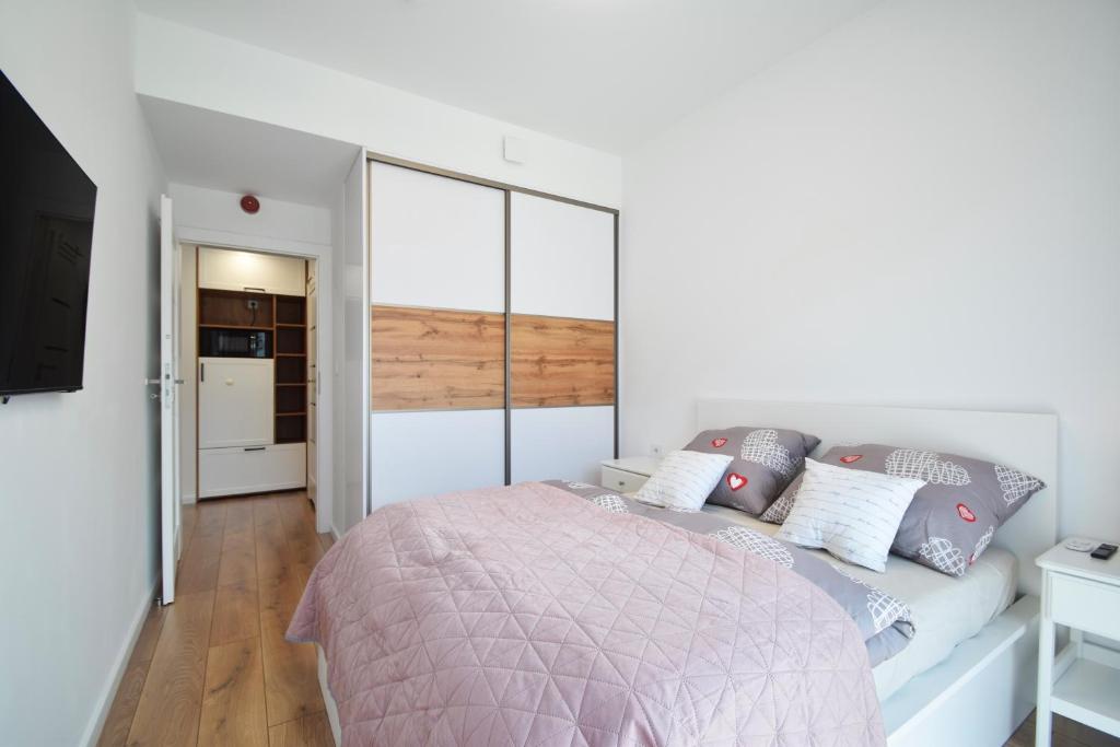 洛格沃Apartament Rogowo的白色卧室配有一张带粉色毯子的床
