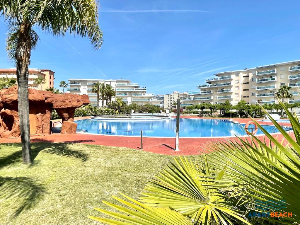 拉皮内达APARTBEACH LOS JUNCOS RESIDENCIAL PISCINAS y PETANCA的一座大型游泳池,位于部分建筑前