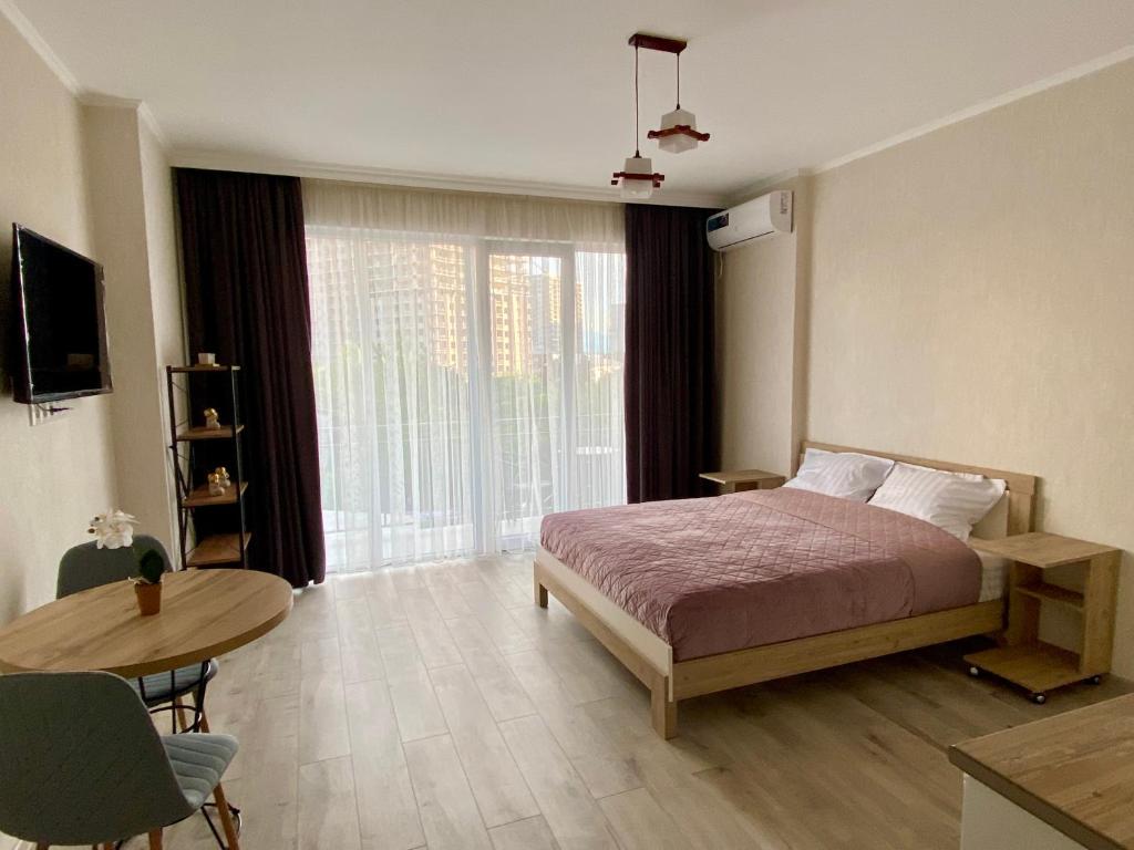 巴统Orange Batumi Travel的一间卧室配有一张床、一张桌子和一个窗户。