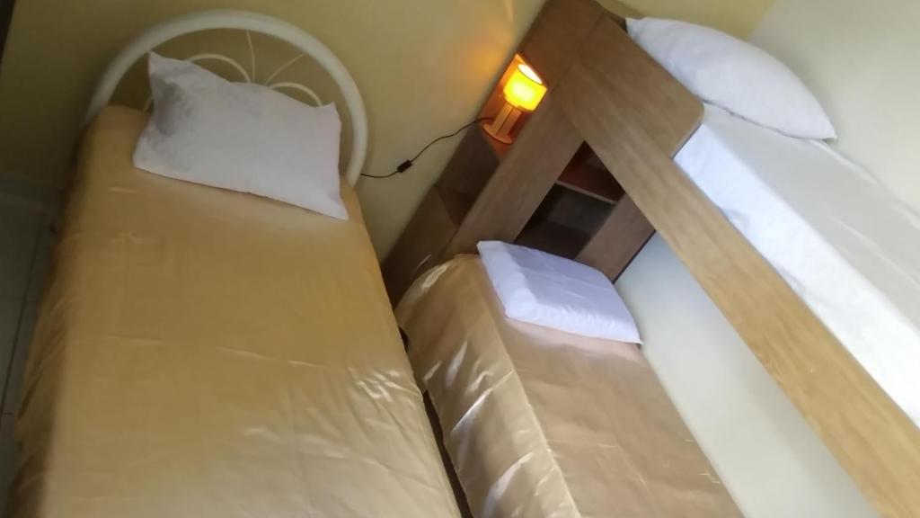 若昂佩索阿Quarto Individual para 3 Pessoas em AP Compartilhado的小型客房配有两张单人床和灯具。