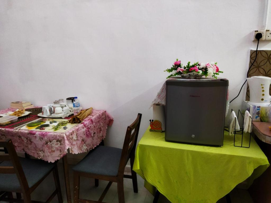 KodiangHOMESTAY UMI KODIANG的一间房间,里面设有两张桌子和一张鲜花桌