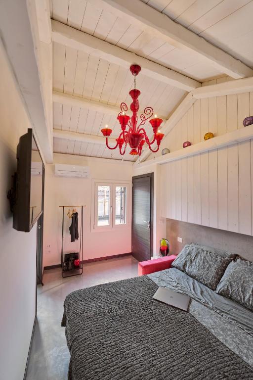 威尼斯Simone Cenedese Murano Apartments - Ambra的一间卧室配有一张大床和一个吊灯。