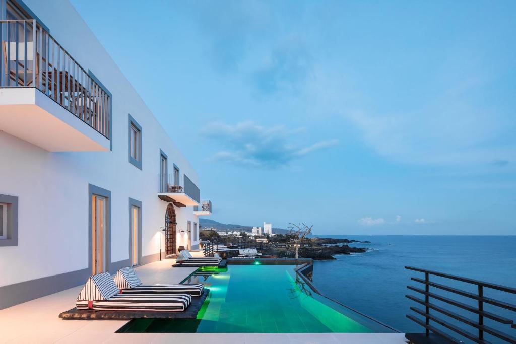 拉戈阿White Exclusive Suites & Villas的一个带躺椅的游泳池和海洋