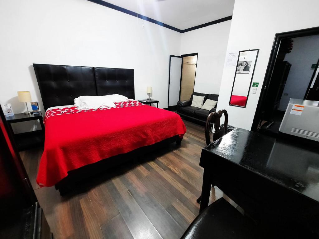 LinaresGarcias Suites y Hotel的一间卧室配有红色的床和钢琴