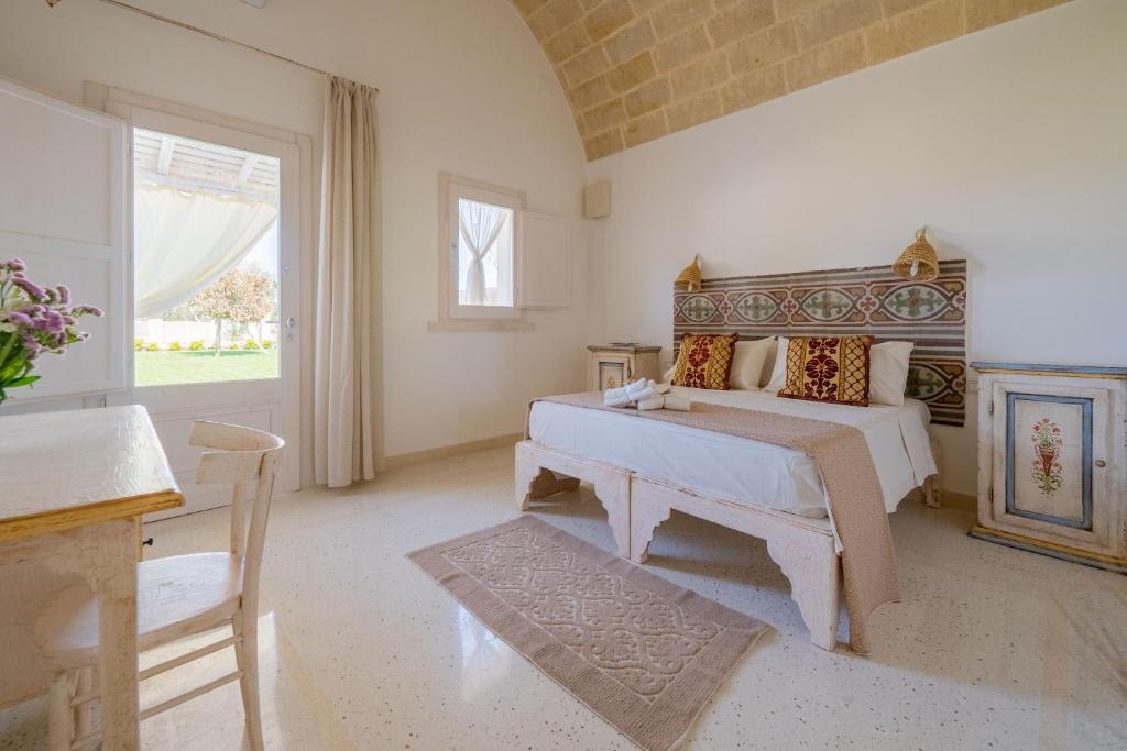 奥特朗托Tenuta Puloni的一间卧室配有一张床、一张桌子和一个窗户。