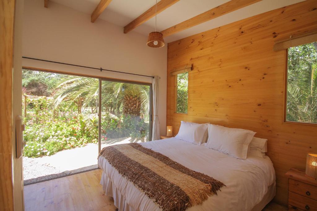 拉塞雷纳Cabañas en la naturaleza a pasos de la Playa的一间卧室设有一张床和一个大窗户