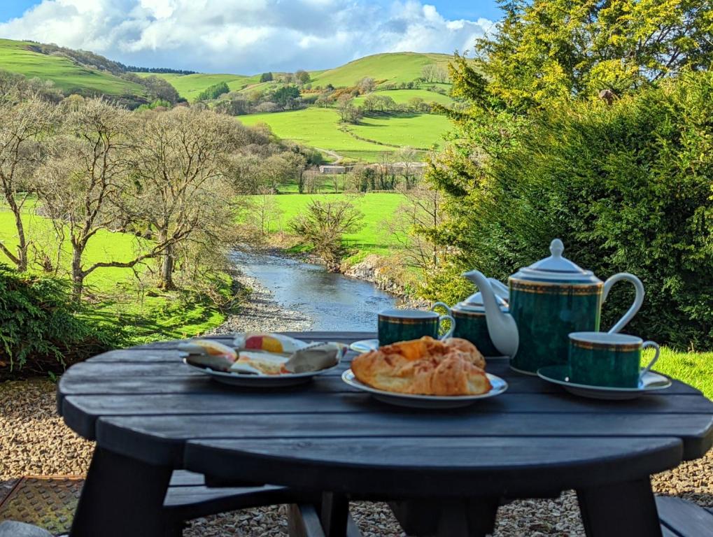 CemmaesAberhiriaeth Hall - Country House By River Dyfi的桌子,上面放着盘子,杯子和一条河