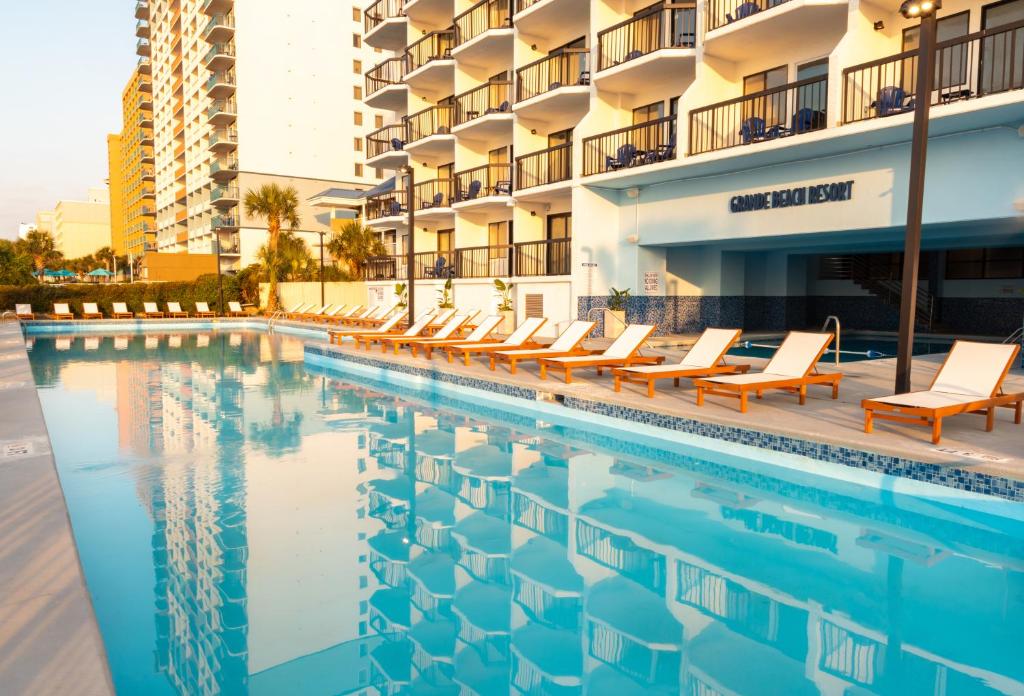 默特尔比奇Grande Beach Resort的一座带躺椅的游泳池位于大楼旁