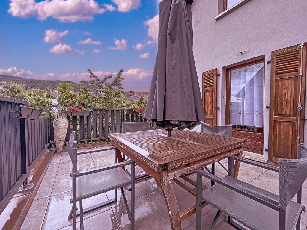 利克维Appartement 2 chambres au cœur du vignoble avec terrasse的阳台上配有一张带椅子和遮阳伞的木桌