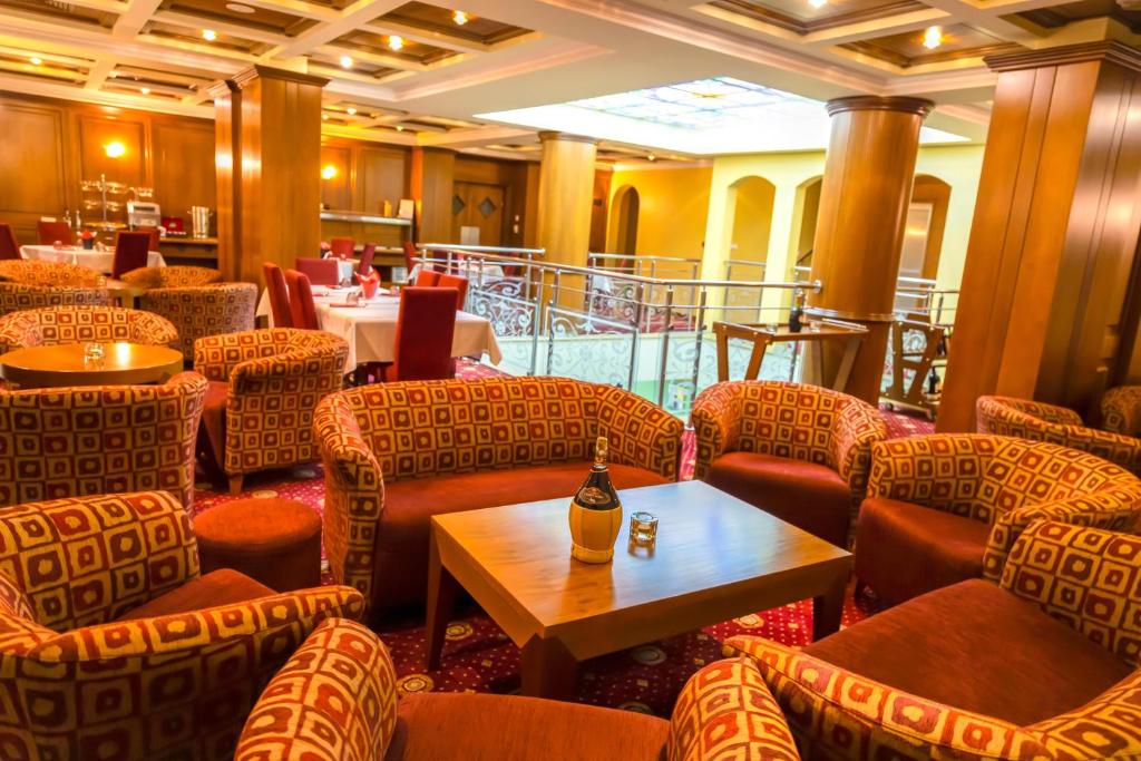 普里什蒂纳Hotel Ambasador Prishtina的餐厅设有椅子和一张桌子,并提供一瓶葡萄酒