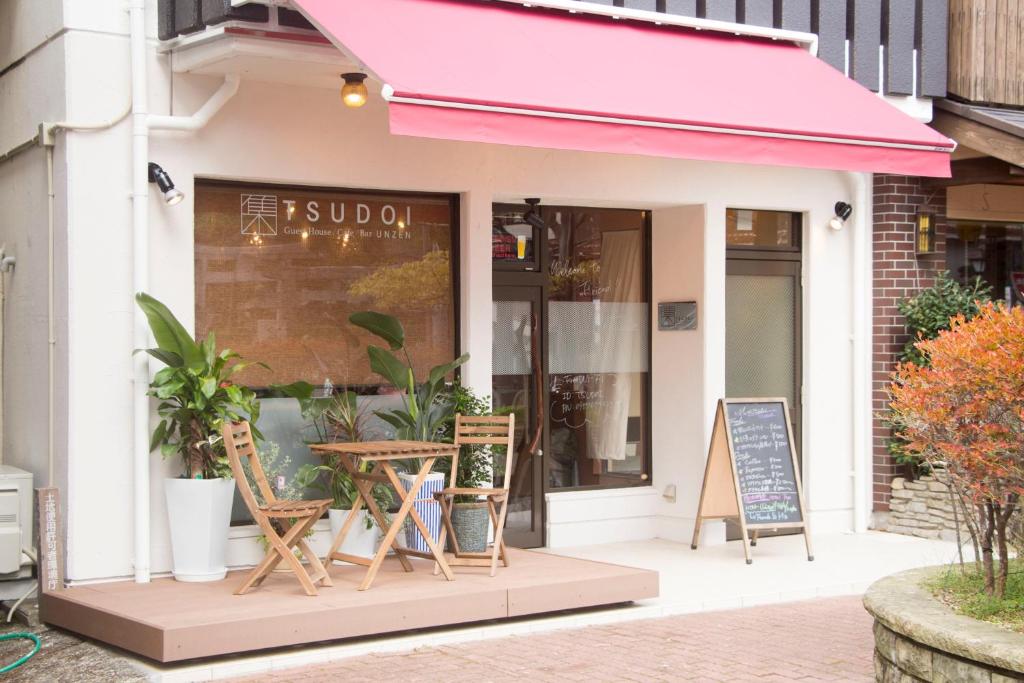 云仙市TSUDOI guest house的路边的咖啡馆,带椅子和粉红色遮阳篷
