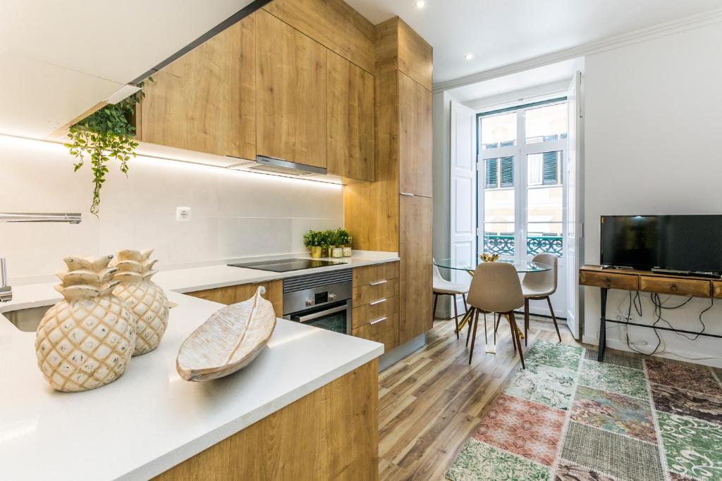 里斯本São José by SpotOn Apartments的厨房配有木制橱柜和一张桌子及一台电视机