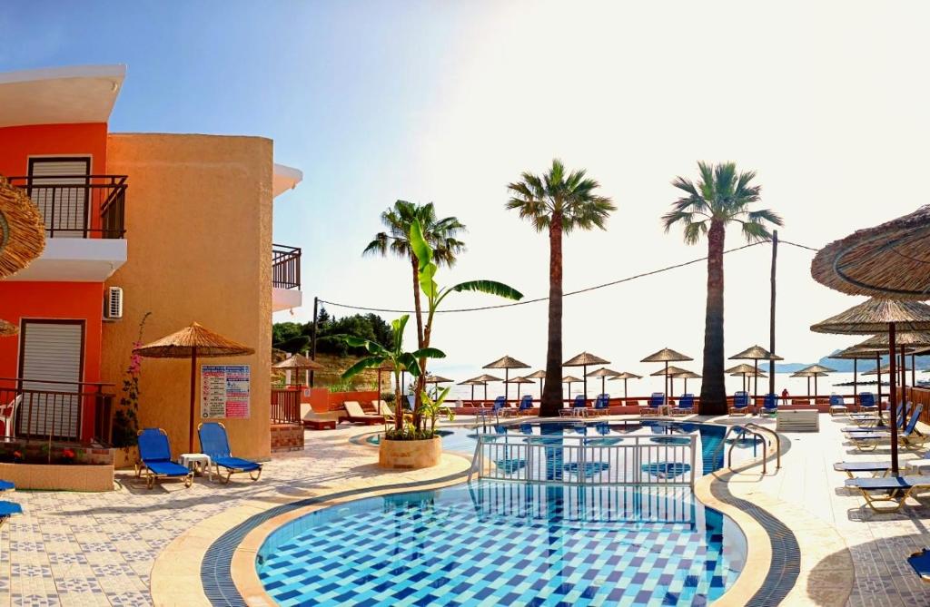 斯达林Maria's Beach Apartments的棕榈树和遮阳伞度假村的游泳池