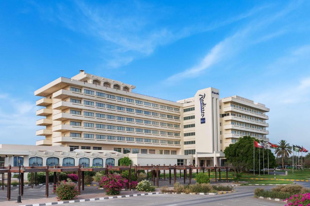 艾恩Radisson Blu Hotel & Resort, Al Ain的停车场前方的白色大建筑