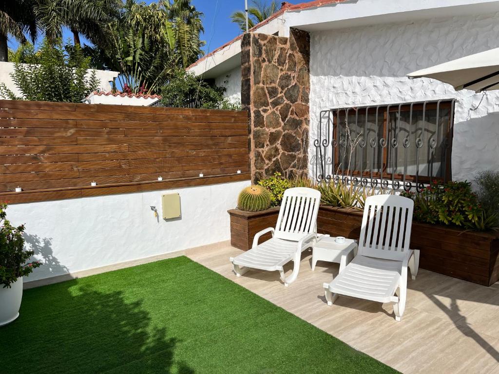 英格兰海滩Bungalow Yumbo的庭院设有两把白色椅子和绿色草坪。