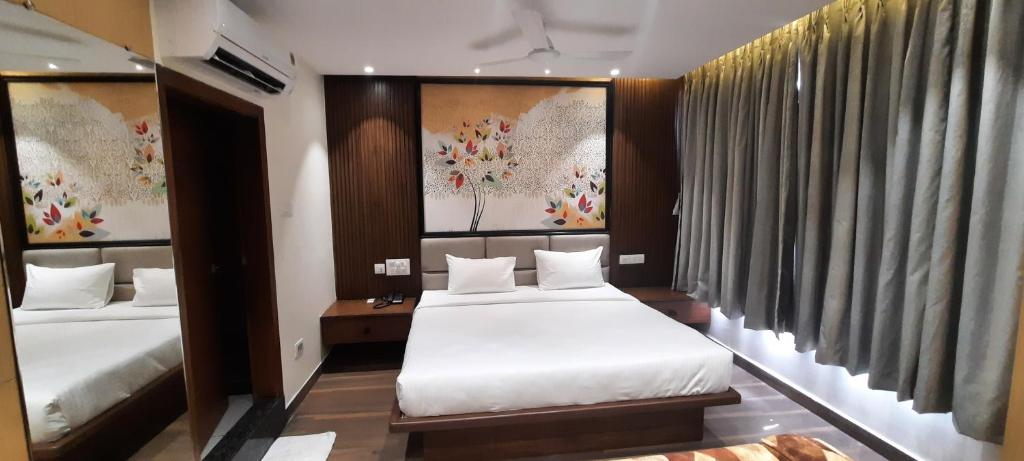 维杰亚瓦达HOTEL SUNRISE HOSPITALITY的酒店客房设有两张床,墙上挂有绘画作品