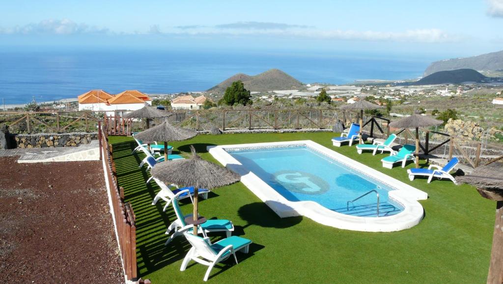洛斯·亚诺斯·德·阿里丹富恩特水疗公寓的一个带椅子和遮阳伞的游泳池以及大海