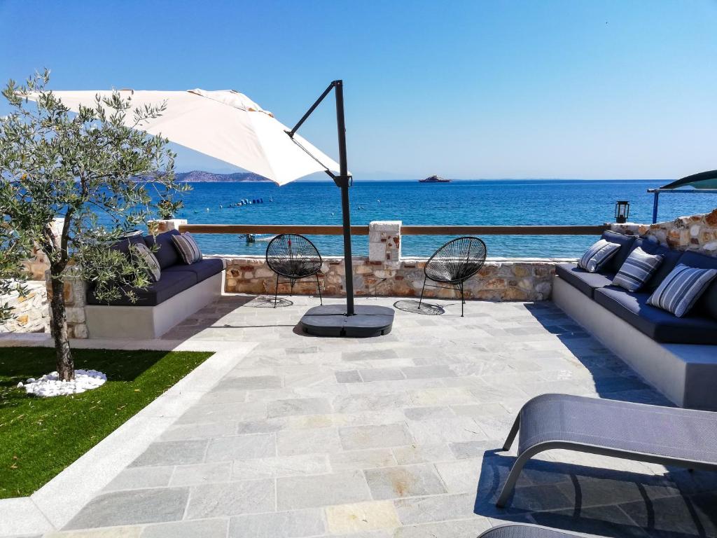 萨索斯Aura di mare luxury house Thassos的一个带沙发和遮阳伞的庭院和大海