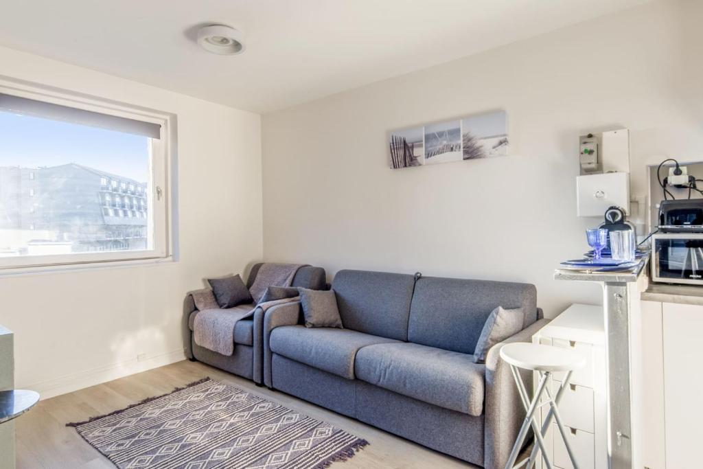 多维尔Nice studio with seaview in Deauville port - Welkeys的客厅设有蓝色的沙发和窗户。