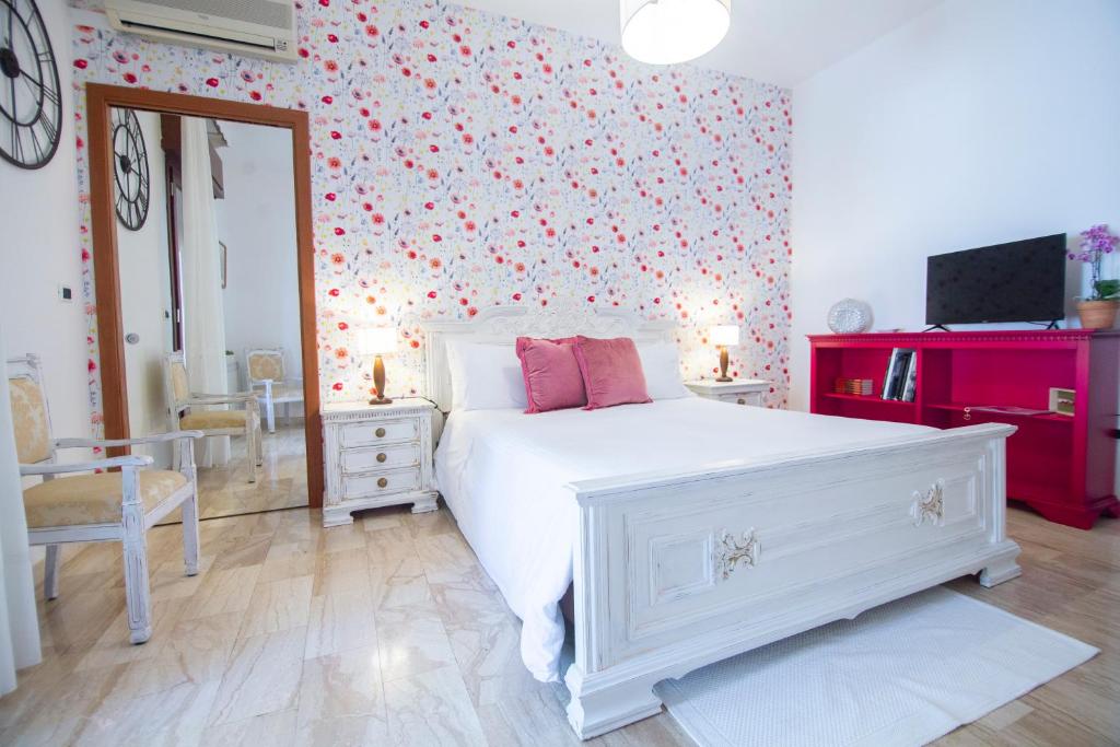 阿尔巴塔克斯B&B Calamoresca的卧室配有白色的床和花卉墙