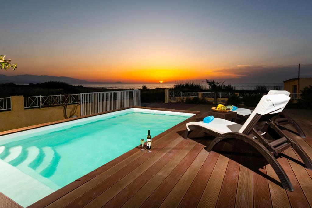 MagnisíaBella Vista House的一个带椅子和一瓶葡萄酒的游泳池