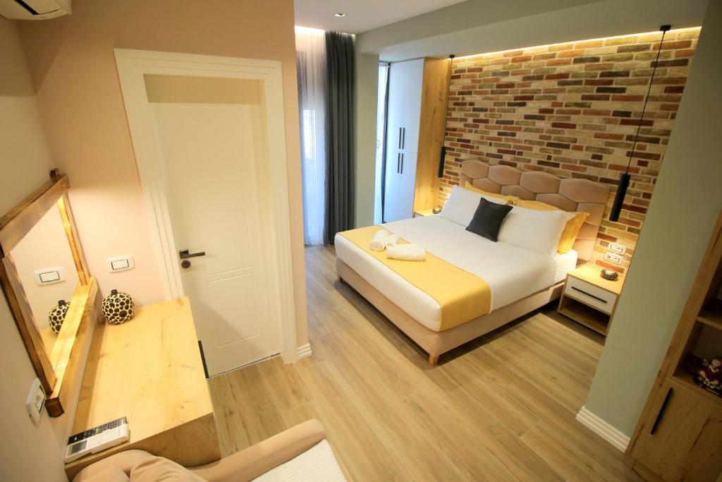 萨兰达Ngjela Apartments的一间卧室设有一张床和砖墙