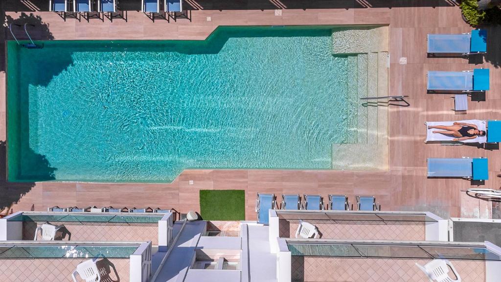 里米尼荣迪内拉维奥拉酒店的游泳池顶部美景,设有椅子