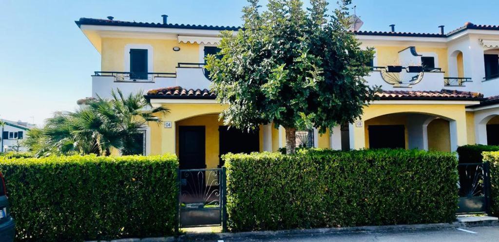 雷卡纳蒂港Villa Claudia a 400m dal mare的前面有灌木的黄色房子