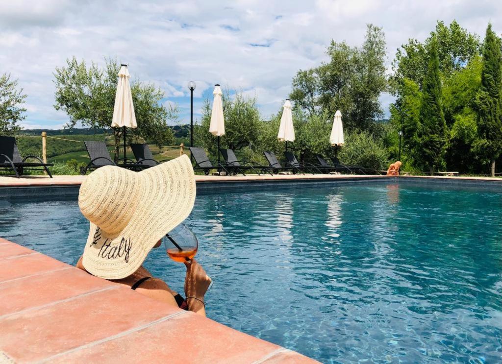拉达-因基安蒂Agriturismo Borgo Il Bonagino的坐在游泳池旁戴草帽的人