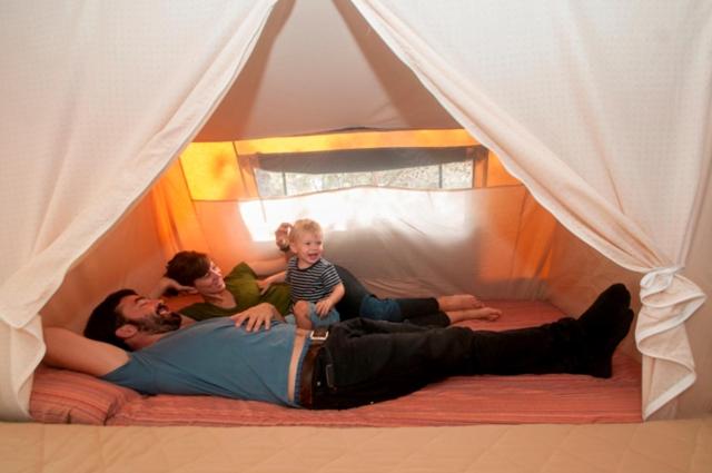Yasocamping yaso-guara的一名男子在帐篷里躺在床上,有两个孩子