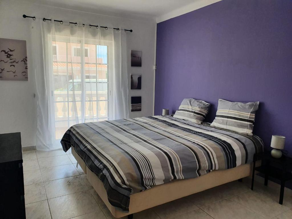拉戈斯Brisa's Haven Guesthouse !Pet Friendly!的一间卧室配有一张紫色墙壁和窗户的床