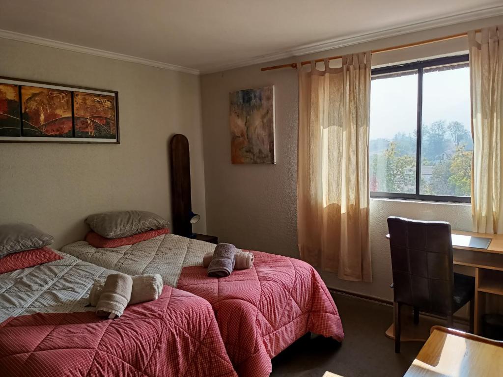 圣地亚哥Habitaciones en Departamento的一间卧室设有两张床、一张桌子和一个窗口。