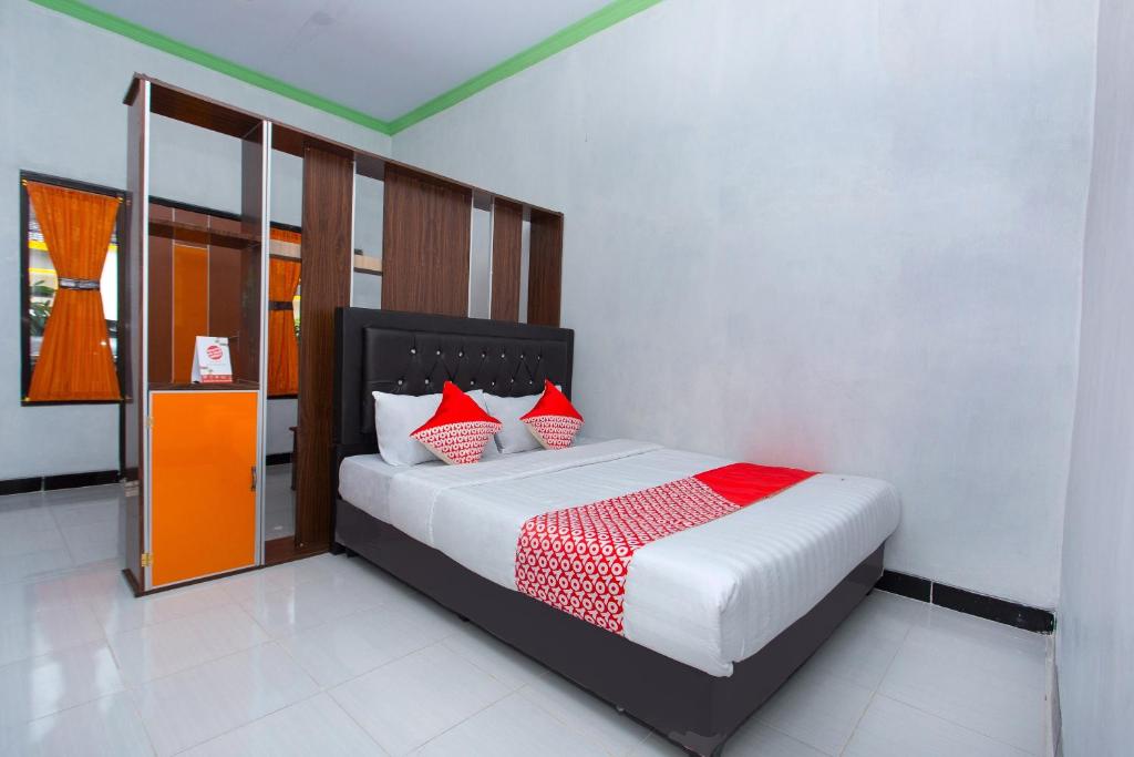 直葛SUPER OYO 2873 Griya Annisa的一间卧室配有红色和白色枕头的床