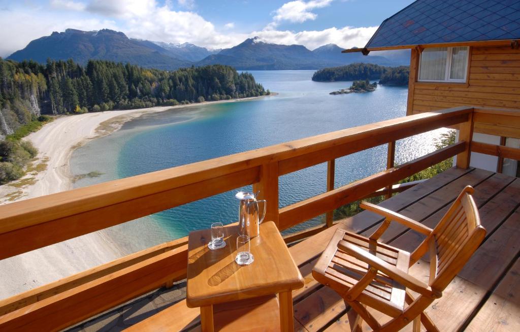Isla VictoriaHostería Isla Victoria Lodge的湖景甲板上的桌椅