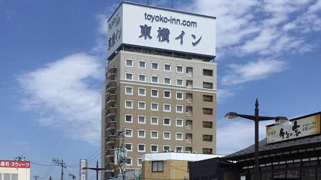 八户市Toyoko Inn Hachinohe Ekimae的一座高大的建筑,上面有标志