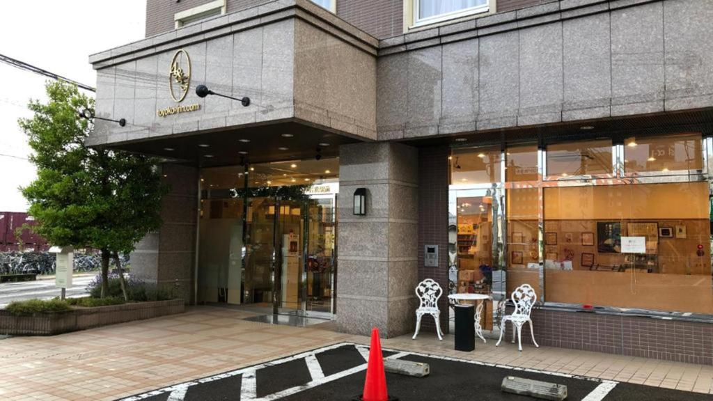 会津若松Toyoko Inn Aizuwakamatsu Ekimae的前方有两把椅子和一张桌子的建筑