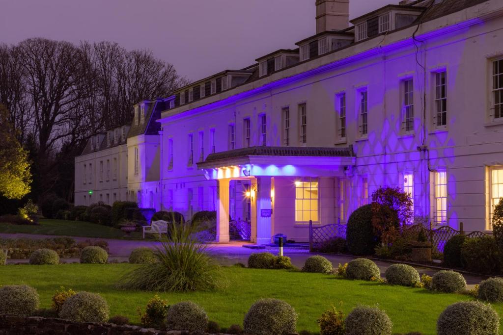 阿伦德尔Avisford Park Hotel的白色的建筑,上面有紫色的灯