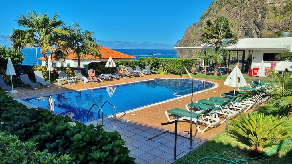 蓬塔德尔加达卡萨达卡普里尼亚酒店的一个带椅子的度假村的游泳池,以及大海
