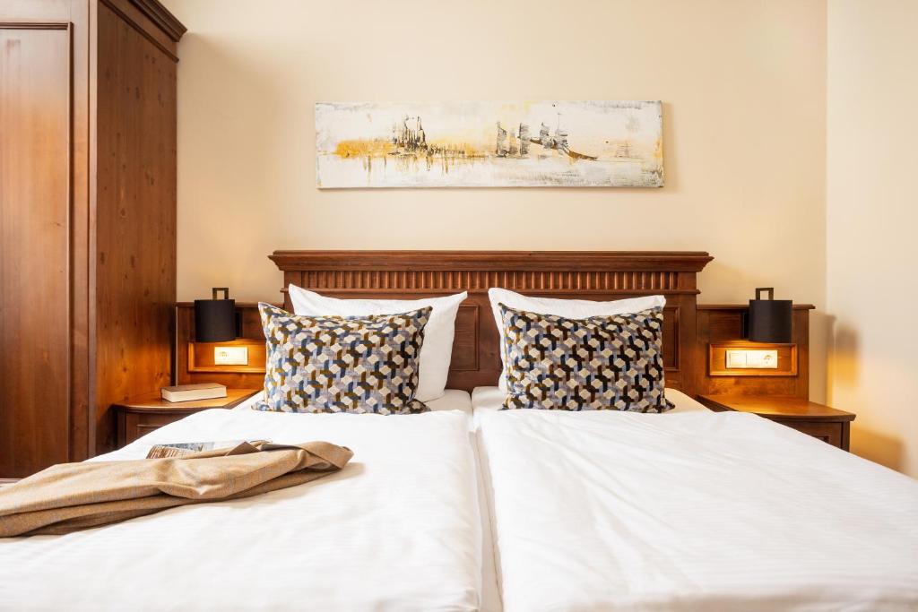 施特拉尔松德老瑞典使馆公寓式酒店的卧室内的两张床,配有白色床单和枕头