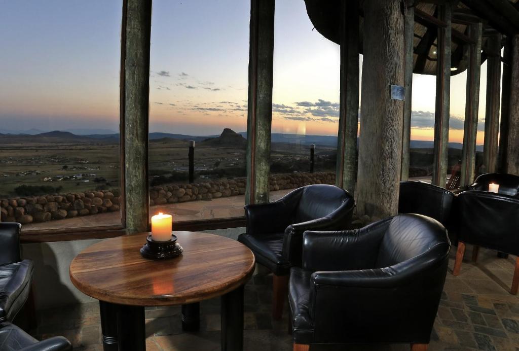 HlazakaziIsandlwana Lodge的配有椅子和一张桌子上的蜡烛的房间