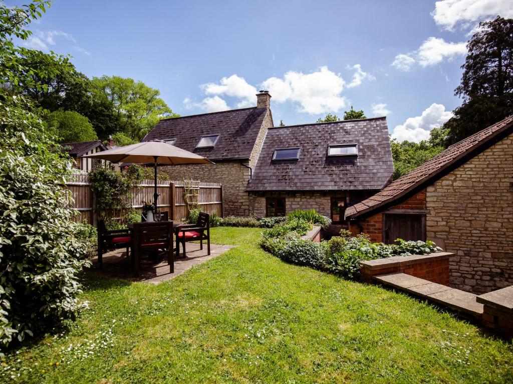 Little WitcombeAmber Cottage的一个带桌子和遮阳伞的花园