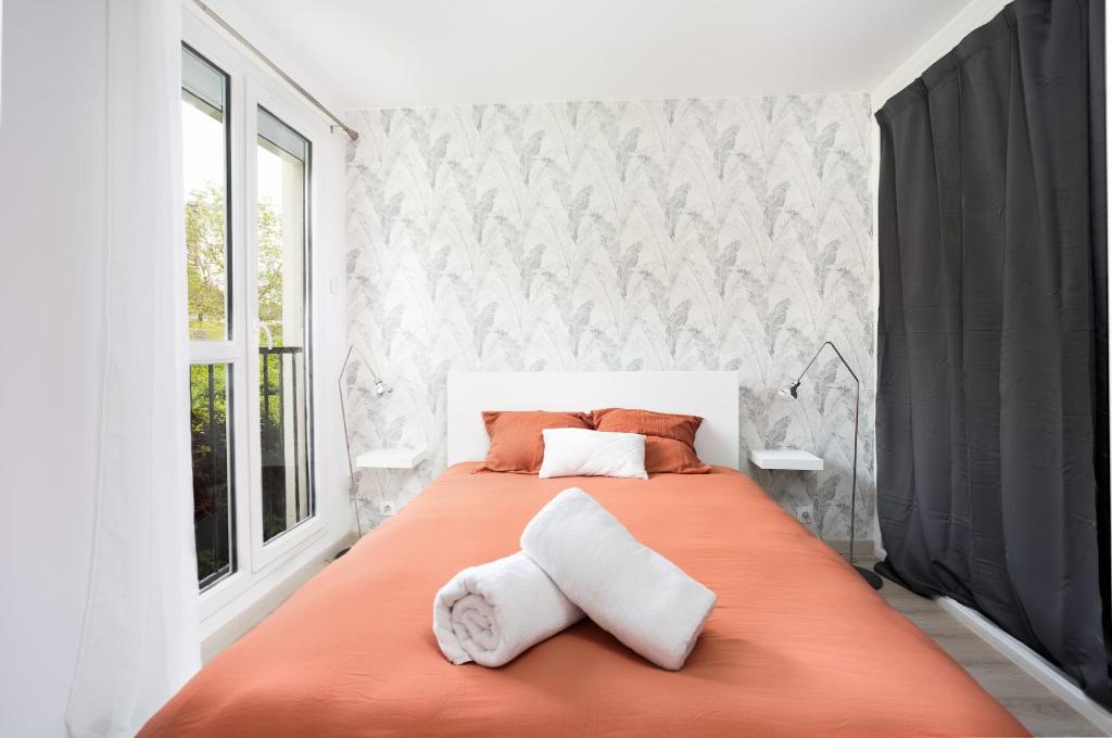 默伦LeCosyMelunais : Parking gratuit + Balcon aménagé的一间卧室配有一张带两个枕头的大型橙色床