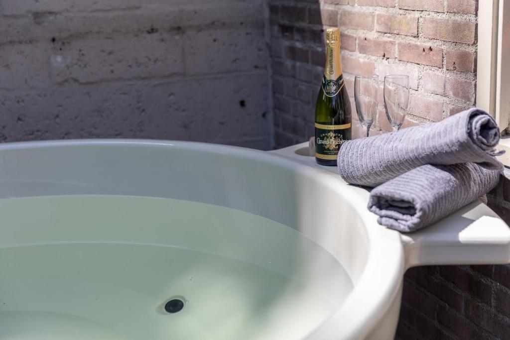 蒂尔堡Museumhuisje 013的浴缸、毛巾和一瓶香槟
