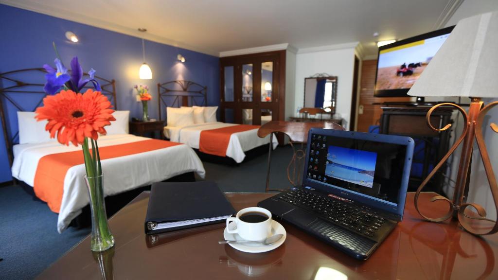 帕丘卡德索托Hotel Ciros的酒店的客房配有带笔记本电脑的书桌和咖啡