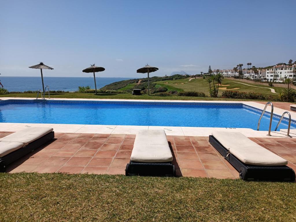 阿尔加德萨Amplio apartamento en Portofino Alcaidesa的度假村内带椅子和遮阳伞的游泳池