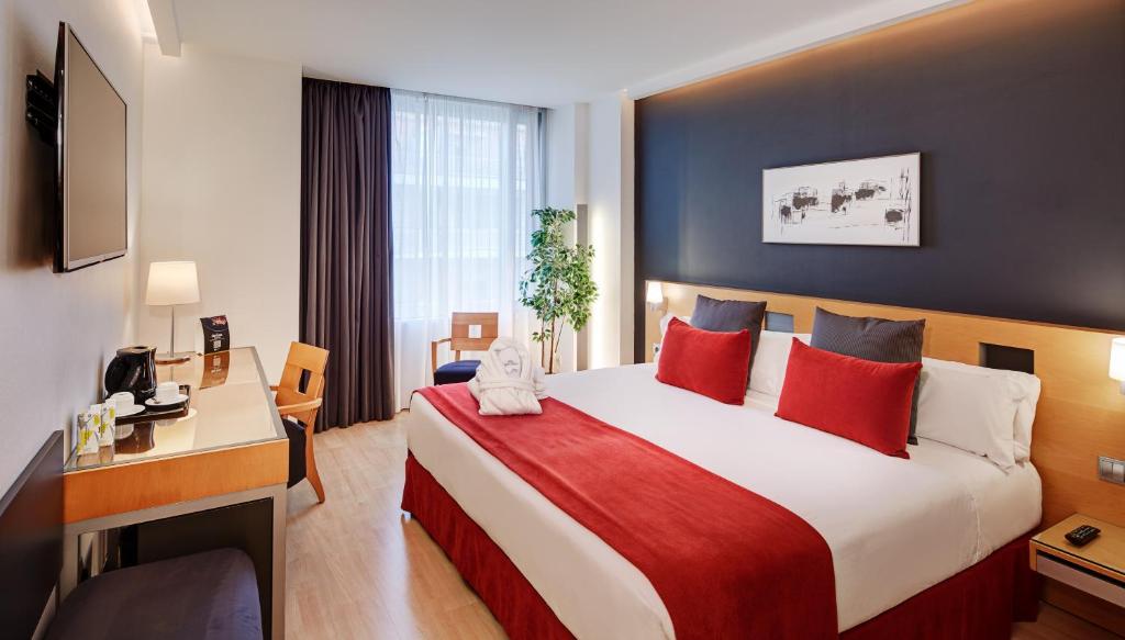 巴塞罗那Sercotel Caspe的酒店客房配有一张带红色枕头的大床