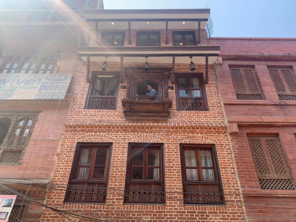 加德满都Studio Apartment at UNESCO Heritage Site的砖房窗户上的男人