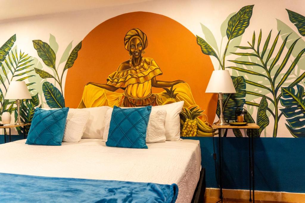 卡塔赫纳Candilejo Hotel Boutique的卧室配有一张特大号床,墙上挂有绘画作品